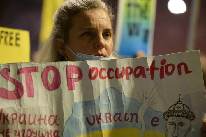 Protester holding a hand-painted sign reading Stop occupation, Ukraine