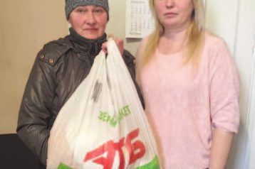 A volunteer hands a food package to a young woman